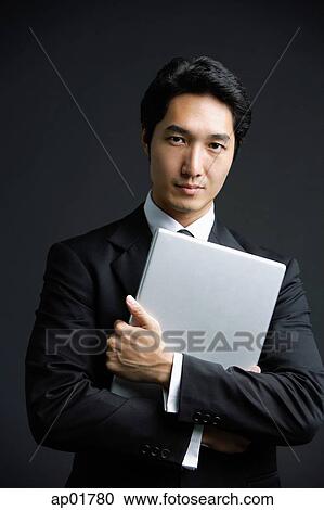 Stock Image - Businessman hugging laptop, looking at camera. Fotosearch