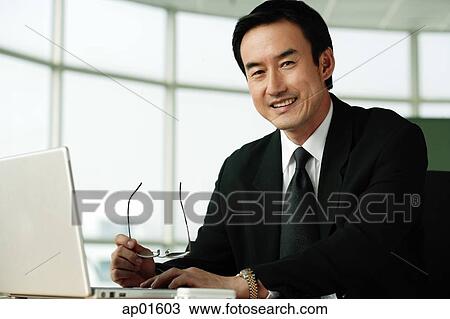 Businessman in office looking at camera, smiling View Large Photo Image Stock Image - Businessman in office looking at camera, smiling. Fotosearch