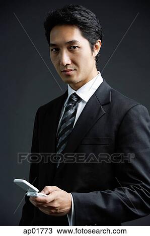 Businessman, looking at camera, holding mobile phone View Large Photo Image Stock Image - Businessman, looking at camera, holding mobile phone. Fotosearch