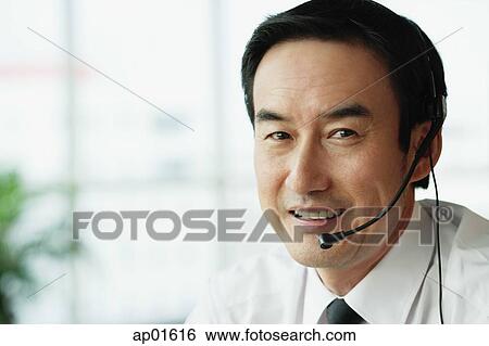 Stock Photograph - Businessman looking at camera, wearing headset. Fotosearch