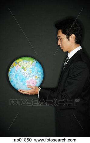 Stock Image - Businessman looking at globe in hands. Fotosearch