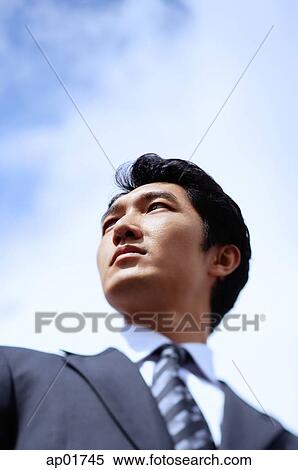 Stock Photography - Businessman, looking away, head shot, low angle view. Fotosearch