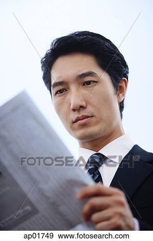 Businessman reading newspaper, serious expression View Large Photo Image Stock Photo - Businessman reading newspaper, serious expression. Fotosearch