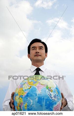 Businessman standing and holding globe View Large Photo Image Stock Image - Businessman standing and holding globe. Fotosearch