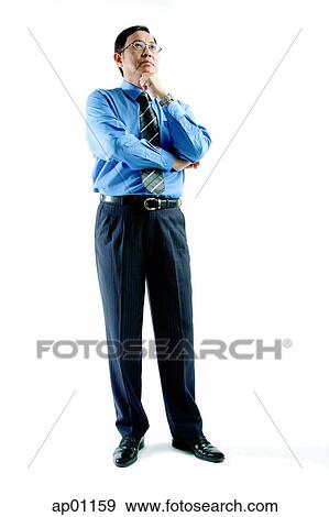 Stock Photo - Businessman standing, arms crossed, hand on chin. Fotosearch