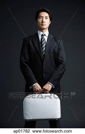 Stock Image - Businessman standing, carrying briefcase. Fotosearch