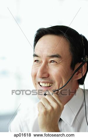 Businessman using headset, smiling, looking away View Large Photo Image Stock Photo - Businessman using headset, smiling, looking away. Fotosearch