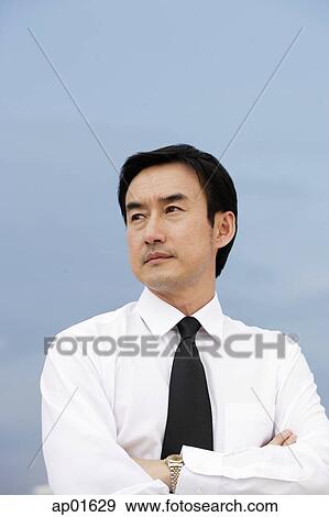 Stock Photo - Businessman with arms crossed, looking away. Fotosearch