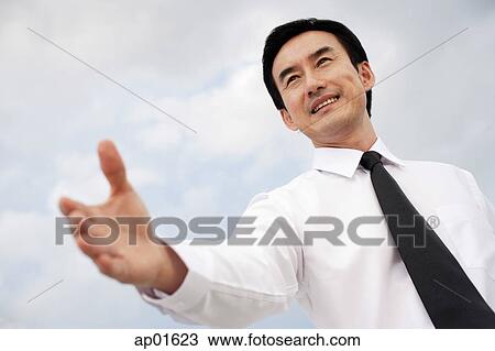 Businessman with hand outstretched, low angle view View Large Photo Image Stock Image - Businessman with hand outstretched, low angle view. Fotosearch