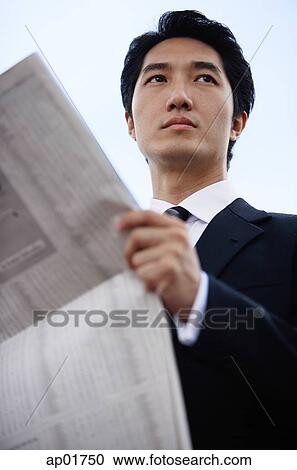 Stock Image - Businessman with newspaper, looking away. Fotosearch