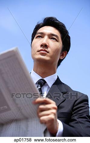 Stock Photo - Businessman with newspaper, looking away. Fotosearch