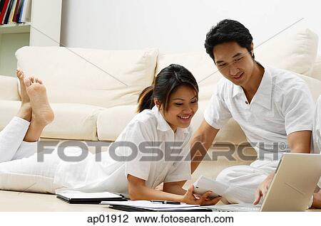 Couple at home looking at laptop View Large Photo Image Stock Image - Couple at home looking at laptop. Fotosearch