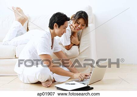 Stock Photo - Couple at home, using laptop. Fotosearch