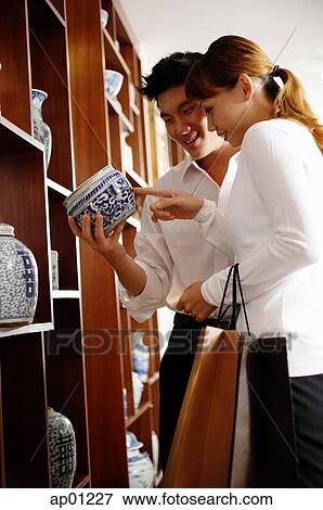 Couple in antique shop, looking at container View Large Photo Image Stock Photo - Couple in antique shop, looking at container. Fotosearch