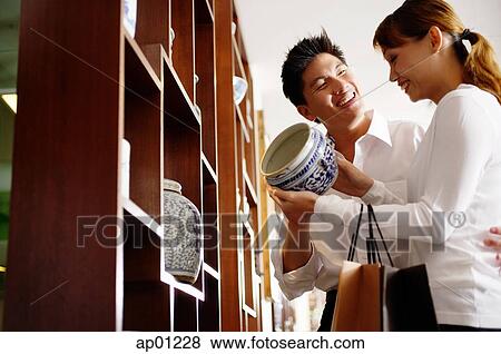 Couple in antique shop, looking at container, smiling View Large Photo Image Stock Photo - Couple in antique shop, looking at container, smiling. Fotosearch