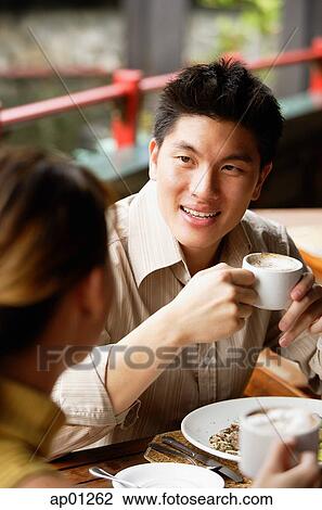 Couple in cafe, man holding cup, looking at woman View Large Photo Image Stock Image - Couple in cafe, man holding cup, looking at woman. Fotosearch