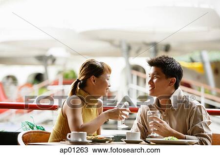 Stock Image - Couple in cafe, sitting side by side. Fotosearch
