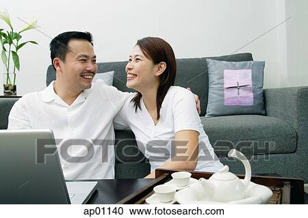 Couple in living room, laughing View Large Photo Image Stock Image - Couple in living room, laughing. Fotosearch