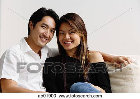 Stock Image - Couple in living room, smiling. Fotosearch