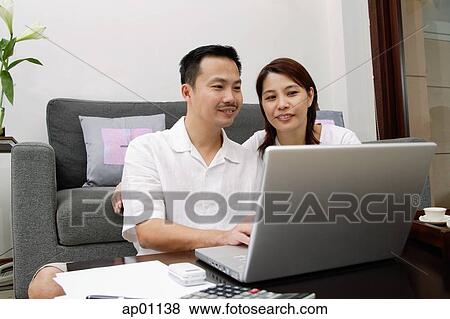 Couple in living room, using laptop View Large Photo Image Stock Photo - Couple in living room, using laptop. Fotosearch