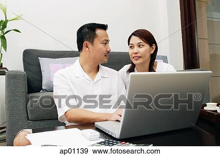 Couple in living room, with laptop View Large Photo Image Stock Photo - Couple in living room, with laptop. Fotosearch