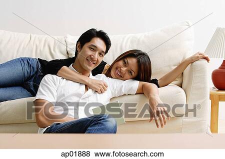 Couple in living room, woman lying on sofa, man sitting on floor in front of her View Large Photo Image Stock Photo - Couple in living room, woman lying on sofa, man sitting on floor in front of her. Fotosearch