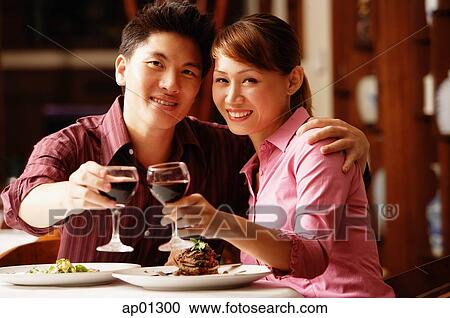 Couple in restaurant, looking at camera, toasting with wine glasses View Large Photo Image Stock Image - Couple in restaurant, looking at camera, toasting with wine glasses. Fotosearch
