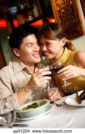 Couple in restaurant, sitting cheek to cheek, holding wine glasses View Large Photo Image Picture - Couple in restaurant, sitting cheek to cheek, holding wine glasses. Fotosearch