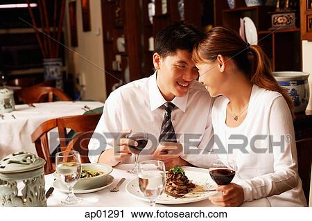 Stock Image - Couple in restaurant, sitting face to face. Fotosearch