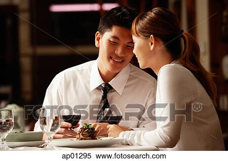 Stock Photography - Couple in restaurant, sitting side by side. Fotosearch