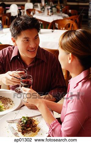 Couple in restaurant, toasting with drinks View Large Photo Image Stock Image - Couple in restaurant, toasting with drinks. Fotosearch