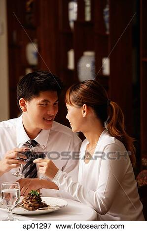 Stock Photo - Couple in restaurant, toasting with wine glasses. Fotosearch