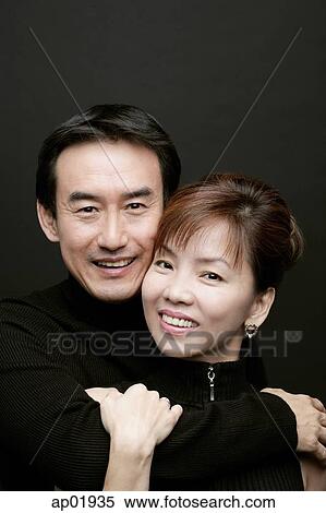 Couple looking at camera, man with arm around woman View Large Photo Image Stock Photography - Couple looking at camera, man with arm around woman. Fotosearch