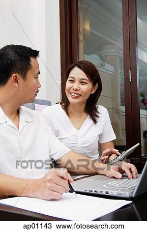 Couple looking at each other, laptop open in front of them View Large Photo Image Stock Image - Couple looking at each other, laptop open in front of them. Fotosearch