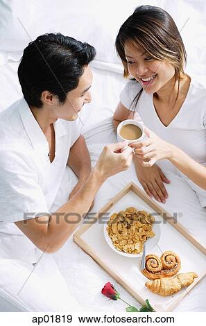 Couple on bed, having breakfast View Large Photo Image Stock Photo - Couple on bed, having breakfast. Fotosearch