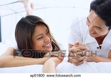 Stock Image - Couple on bed, looking at each other. Fotosearch