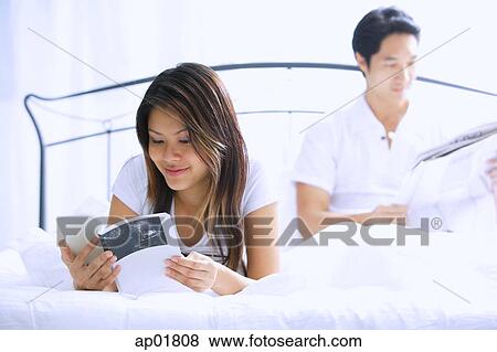 Couple on bed, reading View Large Photo Image Stock Photo - Couple on bed, reading. Fotosearch