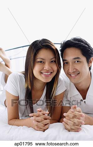 Stock Photography - Couple on bed, smiling at camera. Fotosearch