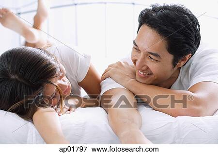Couple side by side on bed, looking at each other View Large Photo Image Stock Photo - Couple side by side on bed, looking at each other. Fotosearch