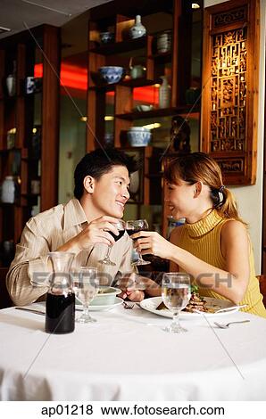 Couple sitting face to face in Chinese restaurant, toasting with wine glasses View Large Photo Image Stock Photo - Couple sitting face to face in Chinese restaurant, toasting with wine glasses. Fotosearch