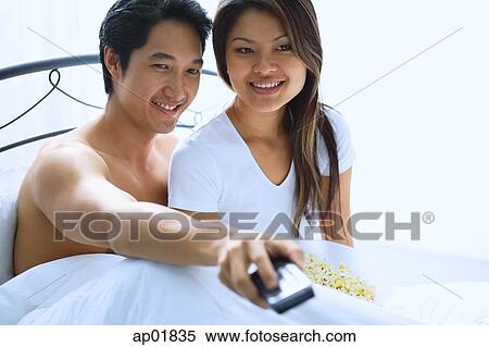 Couple sitting on bed, watching TV View Large Photo Image Stock Photography - Couple sitting on bed, watching TV. Fotosearch