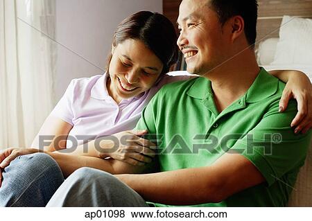 Couple sitting side by side, laughing View Large Photo Image Stock Photo - Couple sitting side by side, laughing. Fotosearch