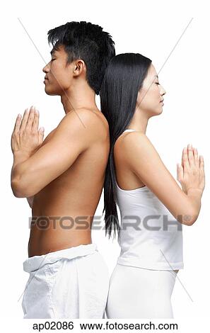 Stock Photograph - Couple standing back to back in yoga position, side view. Fotosearch