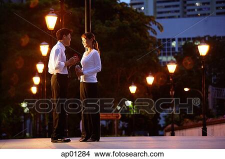 Couple standing face to face, rows of streetlamps behind them View Large Photo Image Picture - Couple standing face to face, rows of streetlamps behind them. Fotosearch