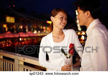 Couple standing face to face, woman holding single rose stalk View Large Photo Image Stock Image - Couple standing face to face, woman holding single rose stalk. Fotosearch