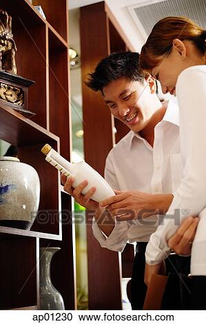 Couple standing next to display in antique shop, looking at bottle View Large Photo Image Stock Image - Couple standing next to display in antique shop, looking at bottle. Fotosearch