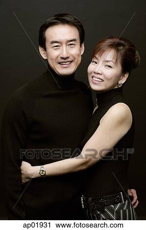 Couple standing side by side, woman with arm around mans waist View Large Photo Image Stock Image - Couple standing side by side, woman with arm around mans waist. Fotosearch