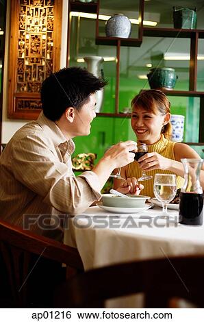 Stock Photograph - Couple toasting with wine glasses in restaurant. Fotosearch
