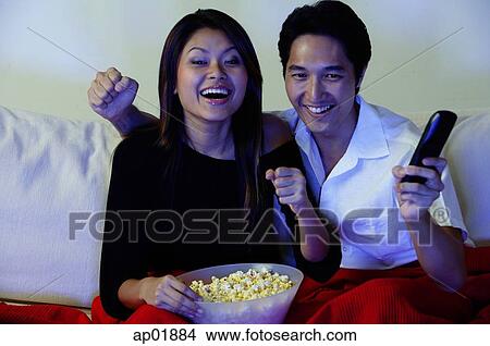 Picture - Couple watching TV, making fists, smiling. Fotosearch