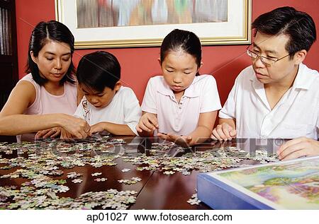 Stock Photo - Family of four fixing jigsaw puzzle. Fotosearch